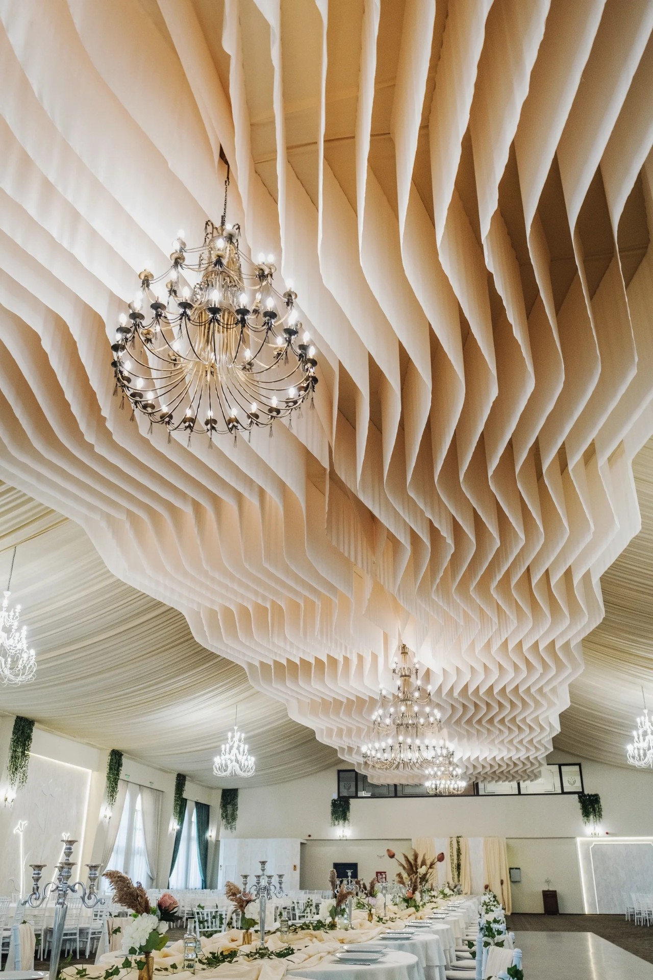 Detaliu de tavan cu draperii ondulate și candelabru central